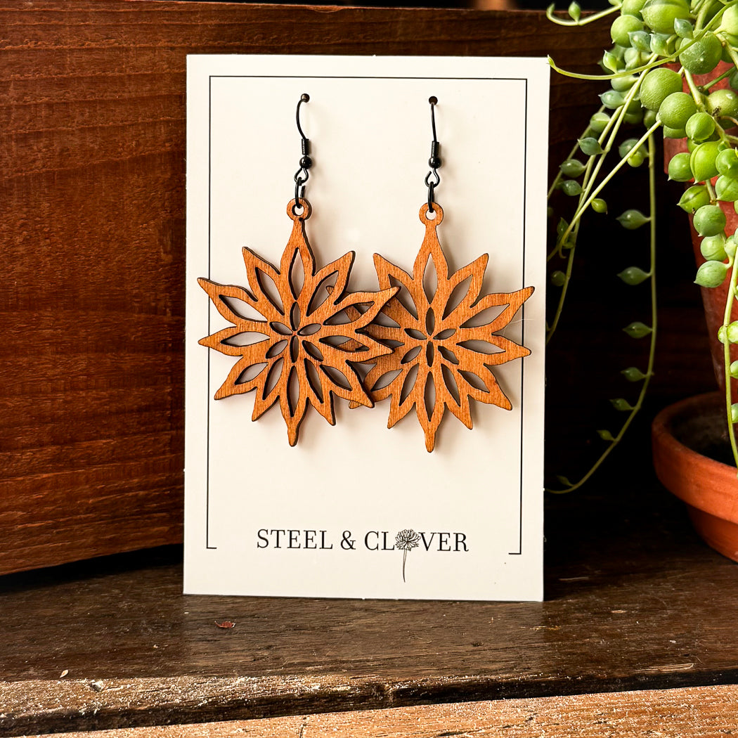 Wooden star-shaped earrings on a 'Steel & Clover' branded card with a wooden background.
