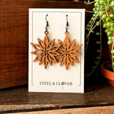 Wooden star-shaped earrings on a 'Steel & Clover' branded card with a wooden background.