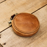 A collection of brown leather coin pouches with a brass lobster clasp, displayed on a wooden surface.