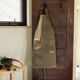 Green apron with brown accents hanging on a wooden door.