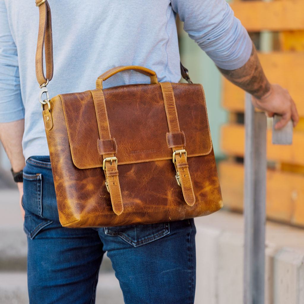 Person wearing a brown leather satchel bag outdoors